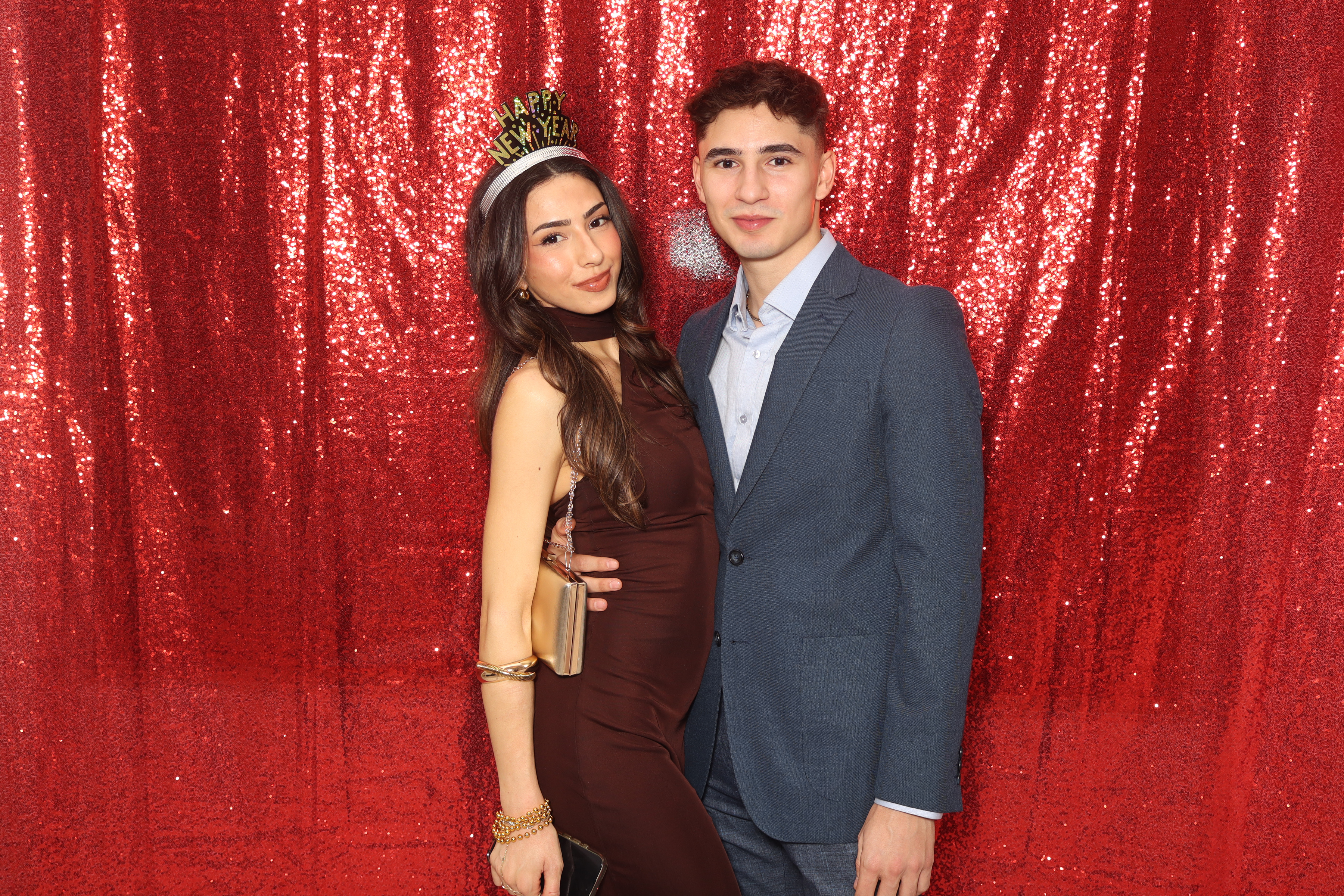 Guests posing at a photo booth in front of a red sequin backdrop